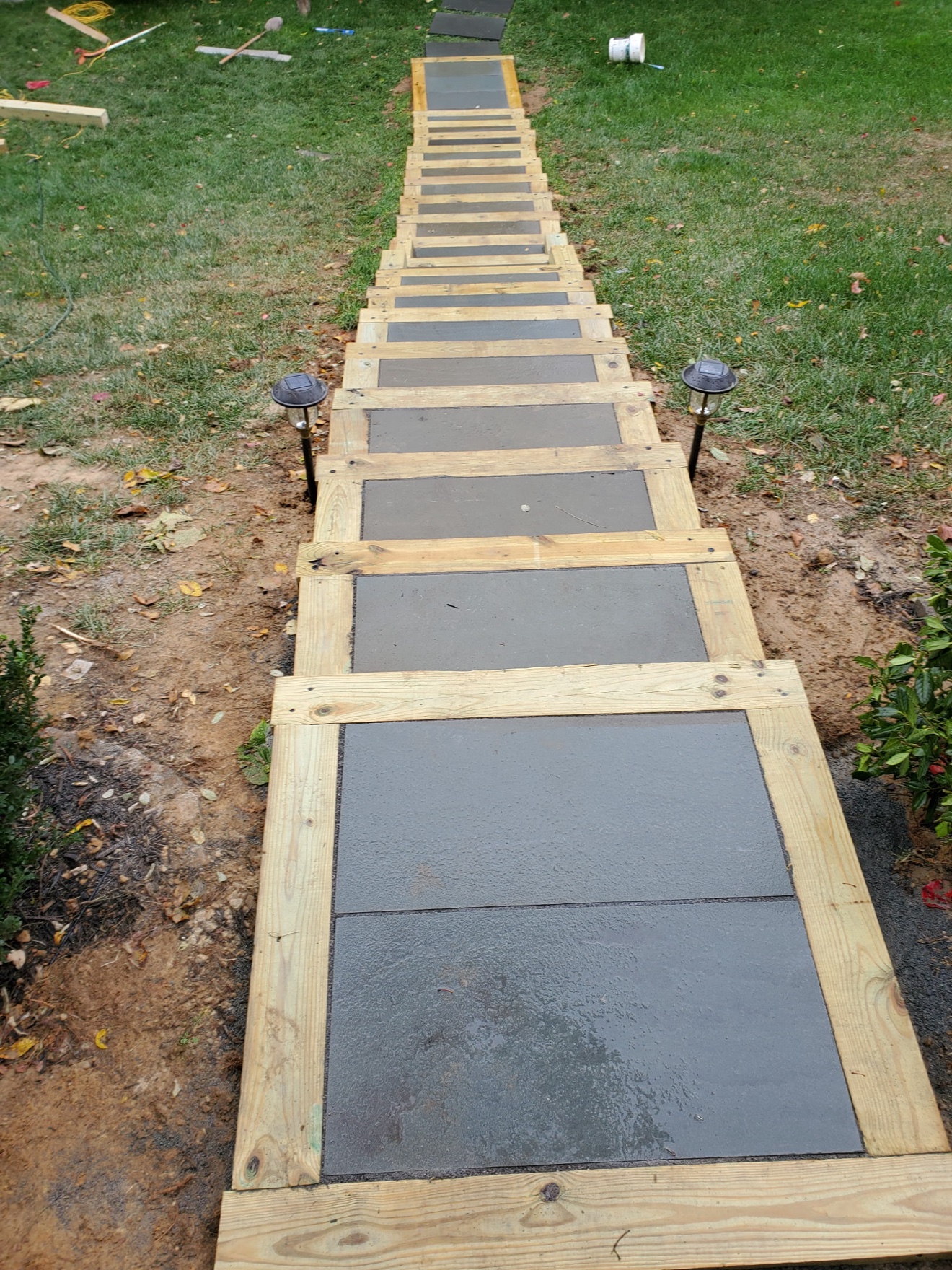 Fresh concrete walkway with timber-framed pads