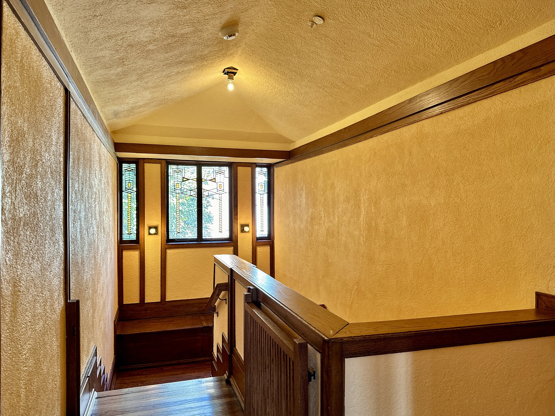 Warm wood hallway and stair landing with art-glass windows